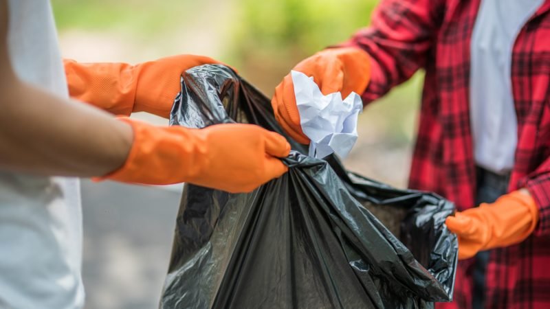 men and women help each other to collect garbage.