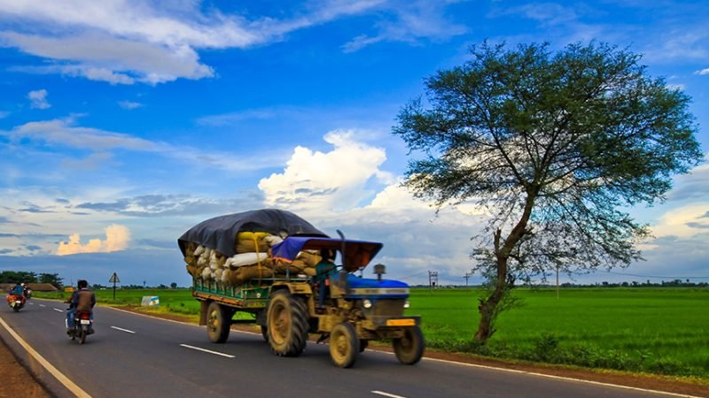 india countryside road and tractor pulling food grains